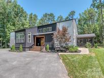Striking modern home with black and gray siding, manicured landscaping, and a welcoming front entrance at 202 Walden Ln, Weddington, NC 28104
