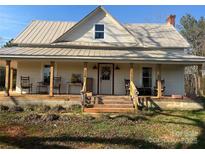 Charming two-story home featuring a welcoming front porch with wooden pillars and a metal roof at 220 Low Water Bridge Rd, Troy, NC 27371