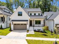 Charming exterior of a white modern farmhouse featuring a gray garage and landscaped front yard at 3949 Plainview Rd, Charlotte, NC 28208