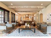 Open-concept living room featuring exposed wood beams, hardwood floors, brick walls and elegant furnishings at 4023 Alexandra Alley Dr, Charlotte, NC 28210