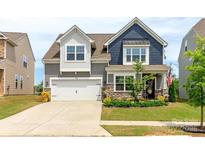 Inviting two-story home features a well-maintained lawn, stone accents, a two-car garage, and charming curb appeal at 4268 Coachwhip Ave, Lancaster, SC 29720