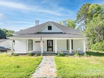 Charming one-story home featuring a covered front porch, gray roof, and well-maintained lawn at 110 College St, Marshville, NC 28103
