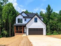 New construction two-story home featuring white siding, black trim, a two-car garage, and a charming front porch at 135 Brookview Dr, Shelby, NC 28152
