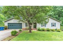 Charming single-story home featuring a blue garage door, lush lawn, and mature landscaping, creating a welcoming curb appeal at 1713 Poe Cir, Hickory, NC 28601