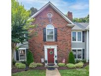 Charming brick townhouse featuring a red front door, black shutters, and manicured landscaping at 1735 Robinwood Rd, Gastonia, NC 28054