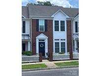Charming brick townhome featuring a white picket fence and a welcoming dark-blue front door at 4103 Christine Ln # E, Waxhaw, NC 28173