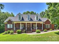 Inviting brick home featuring a covered front porch, manicured lawn, and mature trees at 6309 Chamar Cir, Kannapolis, NC 28081