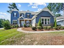 Charming two-story home featuring a covered porch, manicured landscaping, and a beautiful blue exterior at 101 Cross Current Ln, Belmont, NC 28012