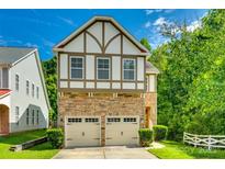 Charming two-story home with a stone-clad facade and a two-car garage, set against a bright blue sky at 13916 Mallard Lake Rd, Charlotte, NC 28262