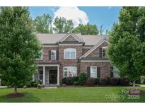 Two-story brick home with meticulously maintained lawn, mature trees, and classic architectural details at 16016 Reynolds Dr, Fort Mill, SC 29707