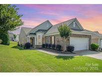 Charming brick home featuring manicured lawn, lush landscaping, and attached two-car garage at 16260 Raven Crest Dr, Indian Land, SC 29707