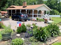 Inviting front yard with lush landscaping and a charming covered porch on a brick home at 169 Smith Clemmer Rd, Mount Holly, NC 28120