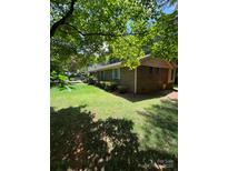 Brick ranch-style home with manicured lawn, featuring light blue shutters and mature tree shade at 2300 Lakeview Cir # 10, Matthews, NC 28105