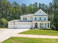 Inviting two-story home with a three-car garage, a basketball hoop, and a charming front porch at 3227 Cape Fox Ct, Denver, NC 28037