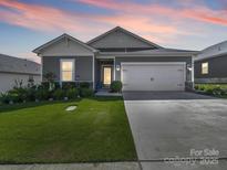 Charming single-Gathering home with a well-manicured lawn and two-car garage at dusk at 3317 Black Cherry Dr, Monroe, NC 28110