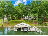 Lake house with a private dock featuring a boat lift, set against a backdrop of lush trees at 698 Normandy Rd, Mooresville, NC 28117