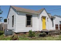 Exterior view of a white home featuring a bright yellow front door and vinyl siding at 1004 S Ridge Ave, Kannapolis, NC 28083