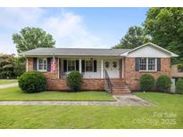 Charming brick home featuring a well-manicured lawn and inviting front porch with double door entry at 115 Fox Run Dr, Fort Mill, SC 29715