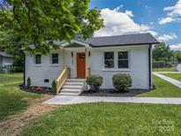 Charming single-story home with painted brick, a well-manicured lawn, and a vibrant orange front door at 132 Kennedy Ave, Kannapolis, NC 28083