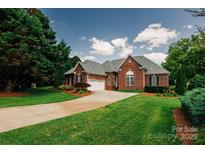 Charming all-brick home featuring a two-car garage, manicured lawn, and mature trees at 225 Northchase Dr, Concord, NC 28027