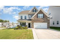 Two-story home featuring a brick and vinyl exterior, attached two-car garage, and manicured front lawn at 5580 Soft Shell Dr, Lancaster, SC 29720