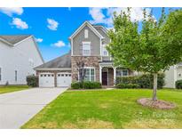 Charming two-story home featuring a stone and gray shingle facade, a well-manicured lawn and a two-car garage at 586 Brookhaven Dr, Fort Mill, SC 29708