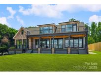 Expansive rear exterior of home with covered porch, stone accents, and well-manicured lawn at 5985 Natoma Rd, Clover, SC 29710