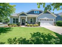 Charming home featuring a well-manicured lawn and inviting covered porch with stone accents and a two-car garage at 658 Gardenbrook Trl, Belmont, NC 28012