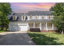 Charming two-story traditional home with a welcoming front porch, two-car garage, and landscaped front yard under a colorful sunset at 6603 Brenock Ln, Charlotte, NC 28269