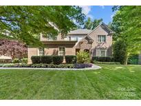 Beautiful brick two-story home with manicured lawn and mature trees, featuring a stone archway at the entrance at 10320 Lemington Dr, Mint Hill, NC 28227
