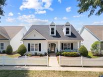 Charming two-story home features a white picket fence and inviting front porch with comfortable seating and landscaping at 1103 Phar Lap Dr, Indian Trail, NC 28079