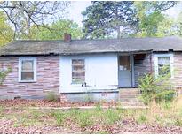 Single story house with brick facade, overgrown yard, and visible signs of neglect, requiring significant renovation at 1554 Forum Ln, Iron Station, NC 28080