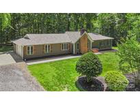Ranch home featuring a brick chimney, shutters, and gravel drive, surrounded by mature trees on a well manicured lawn at 1556 Stanley Lucia Rd, Mount Holly, NC 28120