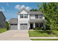 Charming two-story home with a well-maintained lawn, two car garage, and inviting front porch with swing at 389 Whispering Hills Dr, Locust, NC 28097