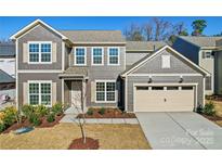 Charming two-story home featuring gray siding, a two-car garage, and manicured landscaping at 1041 Waxhaw Crossing Dr # 058, Waxhaw, NC 28173