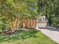 Charming two-story red brick home with attached two-car garage, lush green lawn, and mature shade tree at 11126 Windgate Ct, Tega Cay, SC 29708