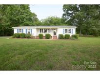 Charming ranch-style home with blue shutters, lush lawn and manicured bushes at 7645 Robinson Church Rd, Harrisburg, NC 28075