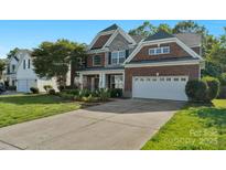 Charming two-story brick home with stone accents, lush landscaping, and a spacious two-car garage at 8325 Burgundy Ridge Dr, Harrisburg, NC 28075