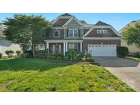 Charming brick and stone two-story home with well-manicured lawn and lush landscaping at 8325 Burgundy Ridge Dr, Harrisburg, NC 28075
