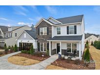 Beautiful two-story home featuring brick and gray siding with a manicured lawn, and rocking chairs on the front porch at 1045 Waxhaw Crossing Dr, Waxhaw, NC 28173