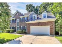 Charming two-story brick home featuring a two-car garage, dormer windows, and well-manicured landscaping at 11305 Hunters Landing Dr, Charlotte, NC 28273