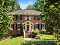 Charming brick home with a manicured lawn, lush trees, and classic architectural details at 1134 Willow Oaks Trl, Matthews, NC 28104
