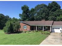 Charming brick home featuring a well-manicured lawn, mature trees, and inviting curb appeal at 137 Proust Rd, Statesville, NC 28625