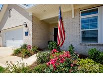 Inviting home entrance with American flag, manicured landscaping, and brick facade at 3006 Constitution Ln, Gastonia, NC 28056