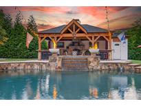 Stunning pool area with an outdoor kitchen and a stone fireplace that is perfect for entertaining guests at 3981 Spinnaker Pl, Denver, NC 28037
