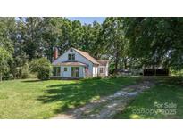 Exterior shot with sunroom, mature trees, and ample green space, offering a blend of comfort and rural charm at 5560 Springs Rd, Conover, NC 28613
