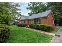 Charming one story brick home with trimmed bushes, green lawn, and mature shade trees in a quiet neighborhood at 5727 Faulconbridge Rd, Charlotte, NC 28227