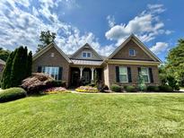 Charming brick home featuring a manicured green lawn and colorful flowerbeds with a beautiful blue sky backdrop at 7076 Brookstone Ln, Fort Mill, SC 29707