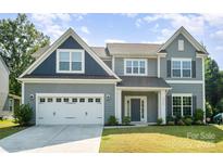 Charming two-story home showcasing a well-manicured lawn and a two-car garage at 12140 Mcdowell Pl, Huntersville, NC 28078