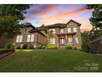 Beautiful stone home features a well-manicured lawn and a charming covered front porch at 16522 Flintrock Falls Ln, Charlotte, NC 28278